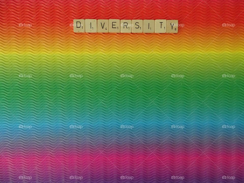 Diversity wooden letters on rainbow background 