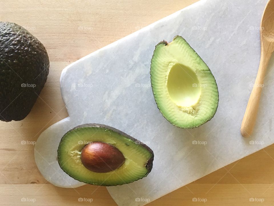 Avocado cut in half on a marble cutting board