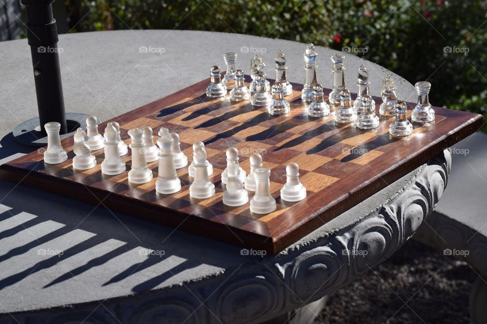 Glass chess set on wooden chessboard