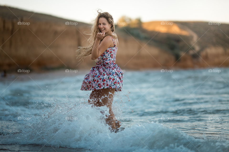 Portrait of beautiful young woman near the sea at sunset