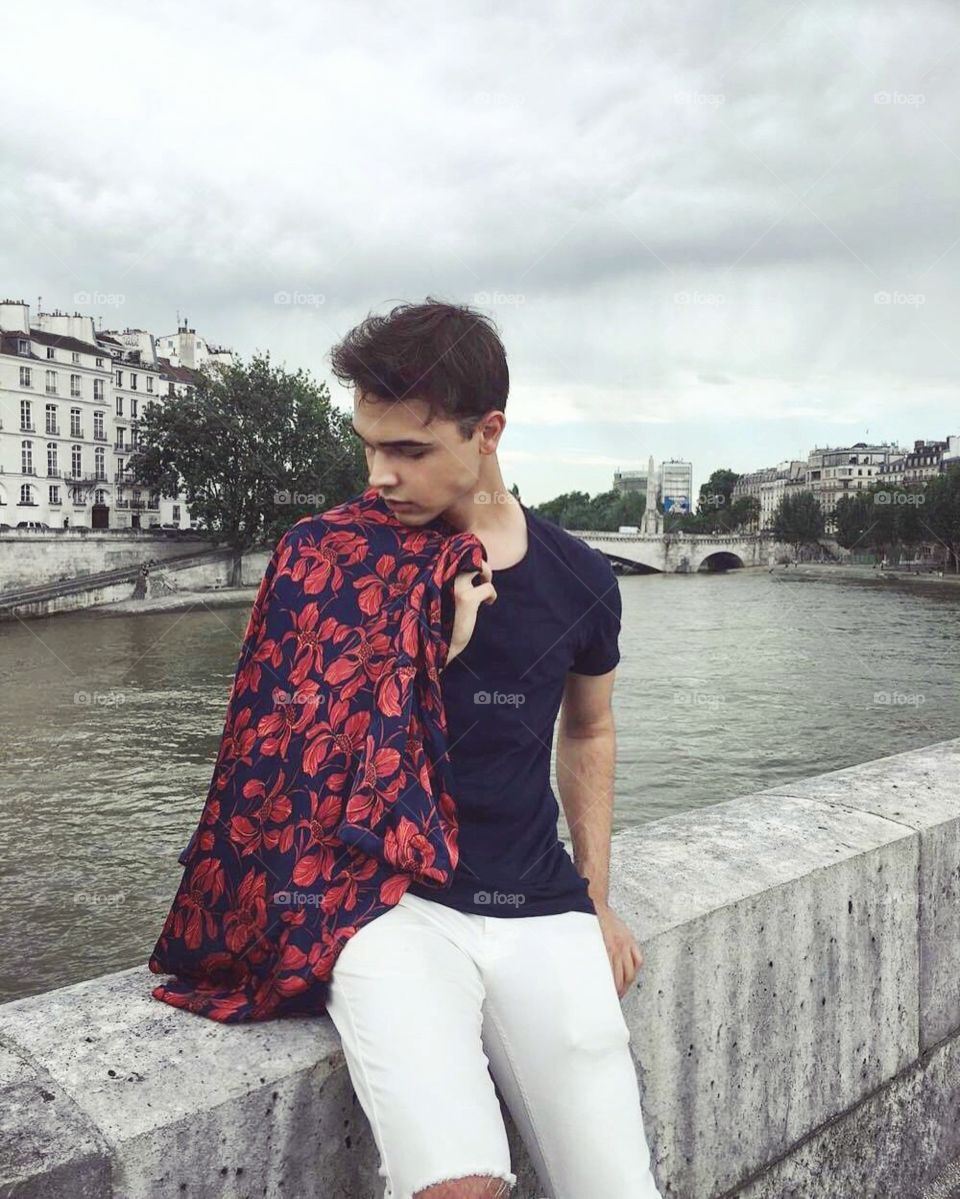 Stylish boy relaxing in front of the Seine in Paris, France 