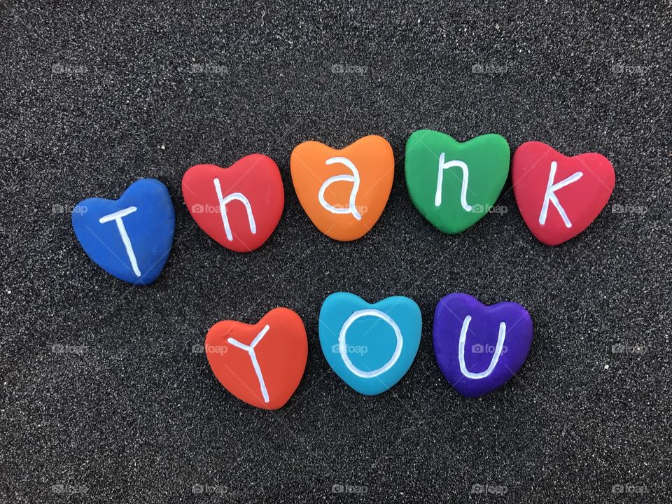 Thank you with colored heart stones over black volcanic sand