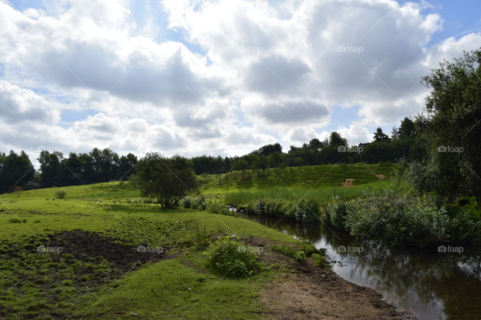 An English countryside with a stream running through the fields. 