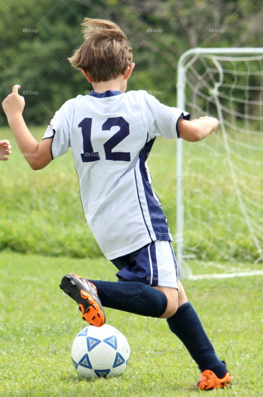 Boy kicking the ball during soccer game 