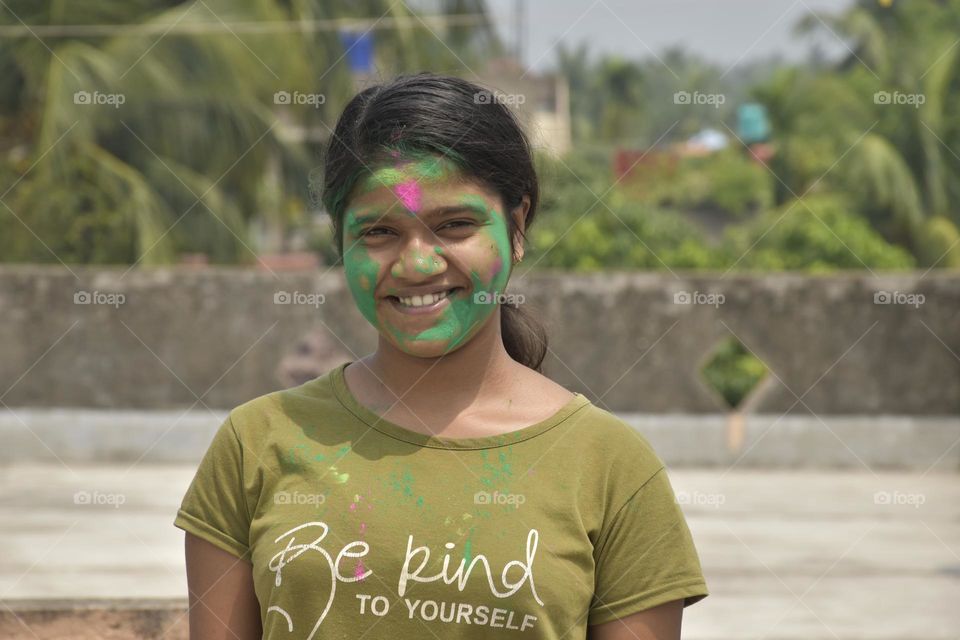 This picture shows a teenage Indian girl enjoying the Holy or Dol festival with abir. She is smiling with joy. Holy or Dol is an Indian festival which is a festival of color related to Lord Shree Krishna.