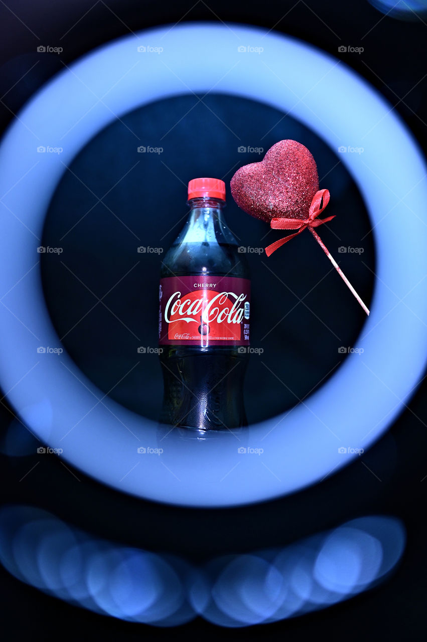 Close up shot of two Coca Cola with black background with the mists at the studio with hearts, with light rings. 