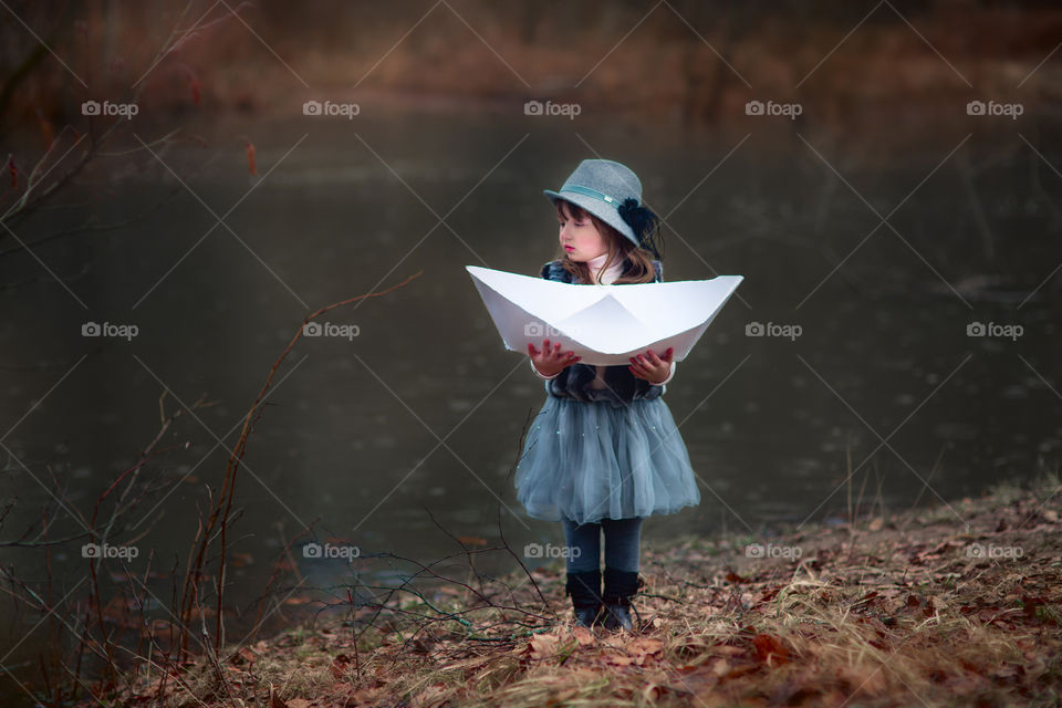 Little girl with paper boats at spring river