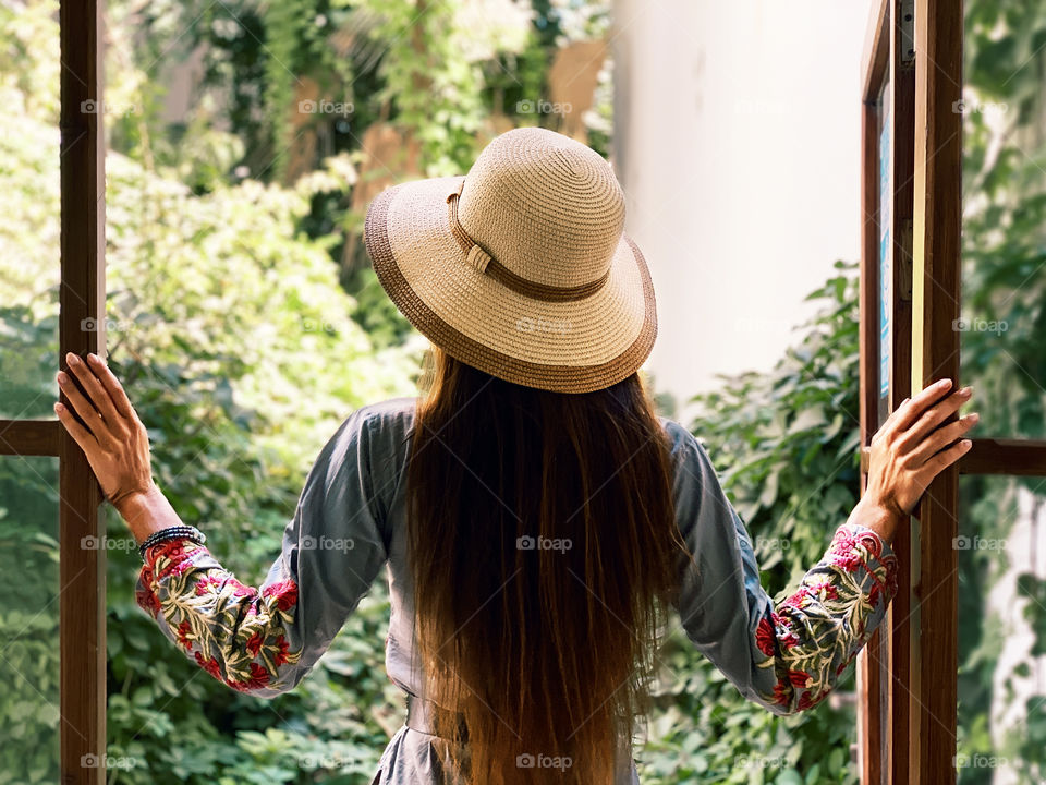 Young woman with long hair standing in front of opened window 