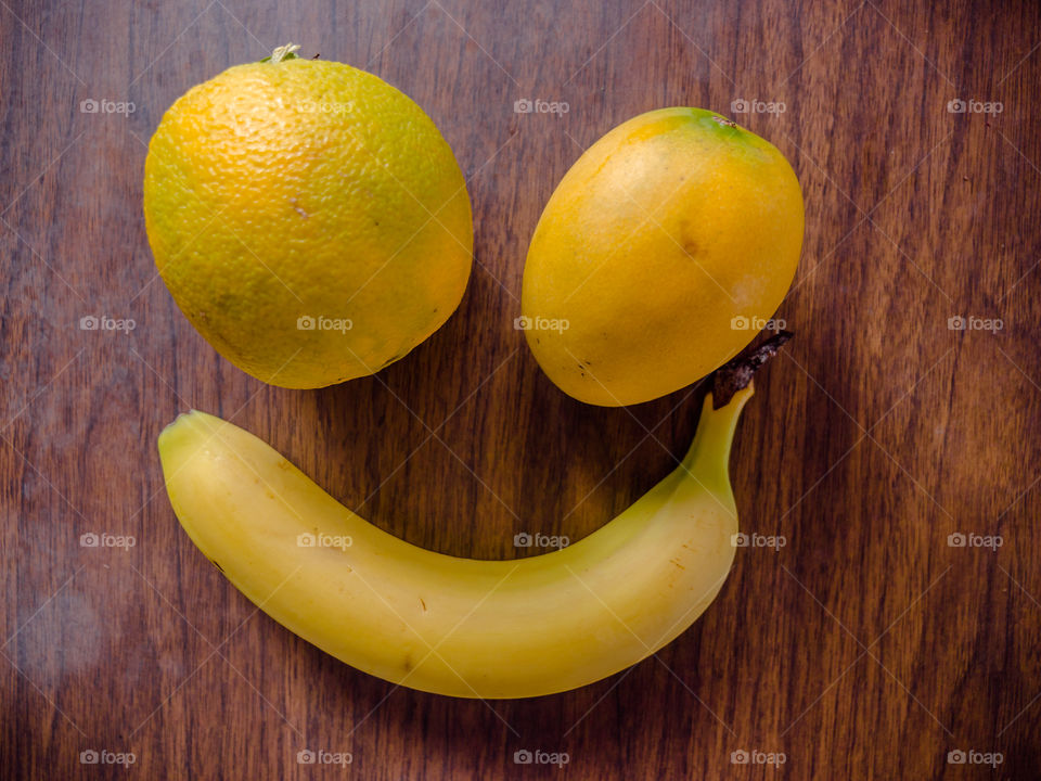 Fresh fruits on table. Orange, banana and mango on a wooden table