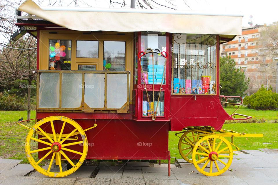 Small colorful mobile candy store on wheels.  It has a circle,  rectangle, and triangle