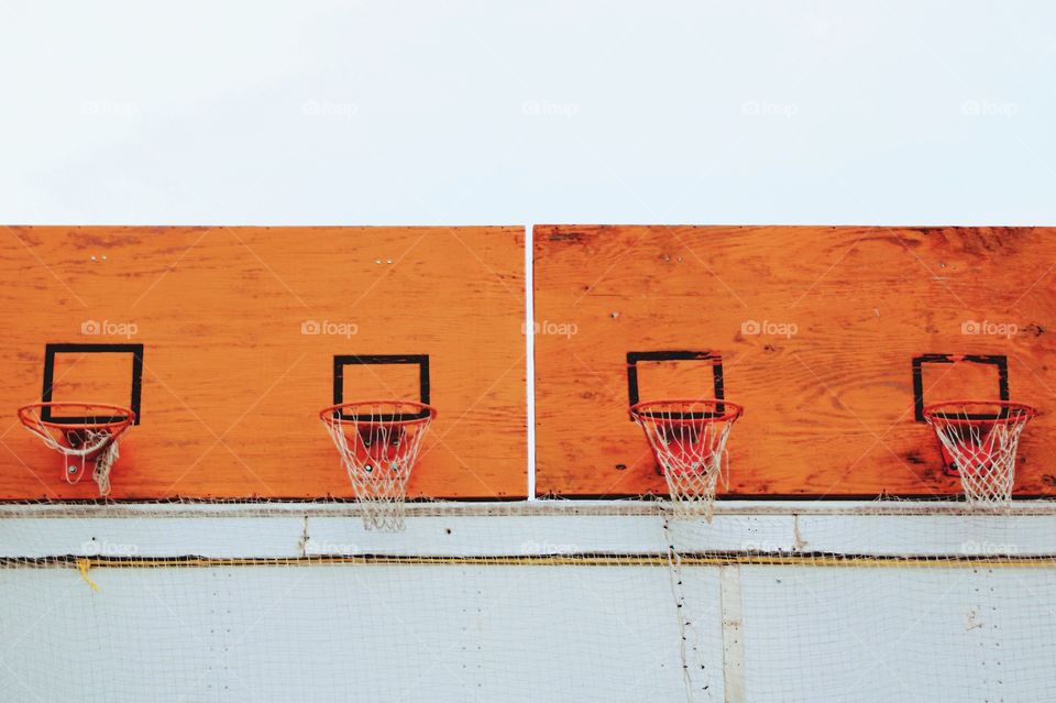 Shapes: Rectangle - Basketball hoops with nets on weathered, orange, playwood backboards