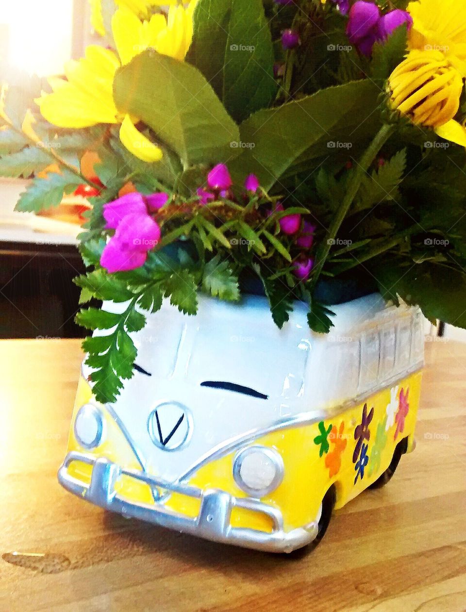 Volkswagen Hippie Van Flower Pot. Bright yellow flower pot with an assortment of beautiful flowers.