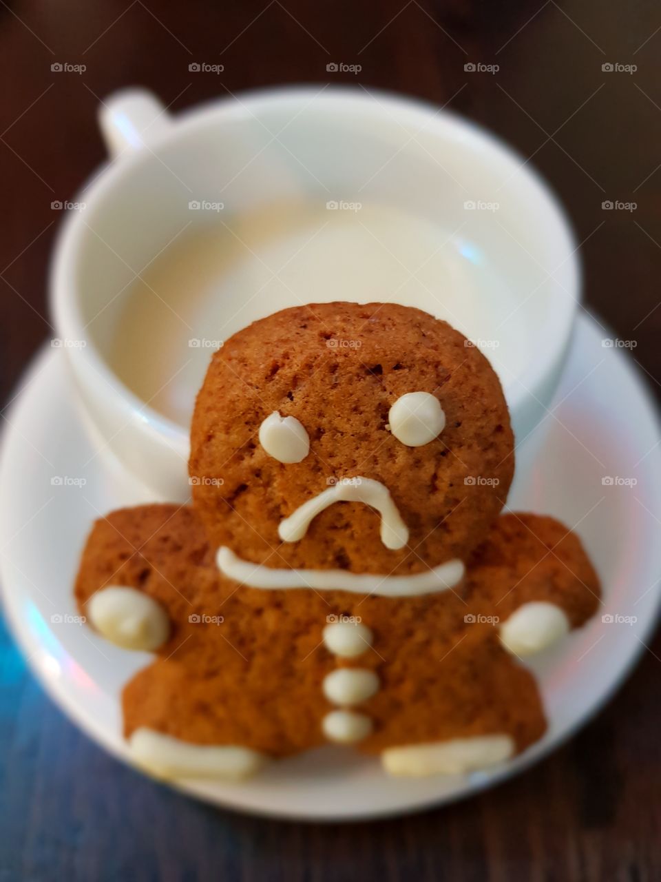 Sad gingerbread cookie front of a white chocolate cup