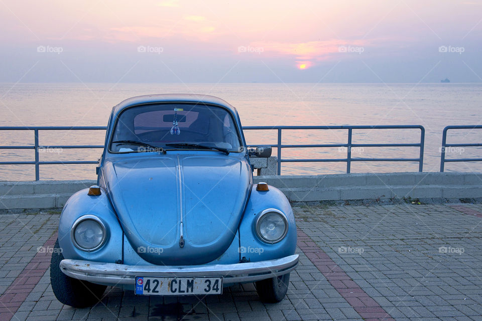 a blue old car on a seaside background