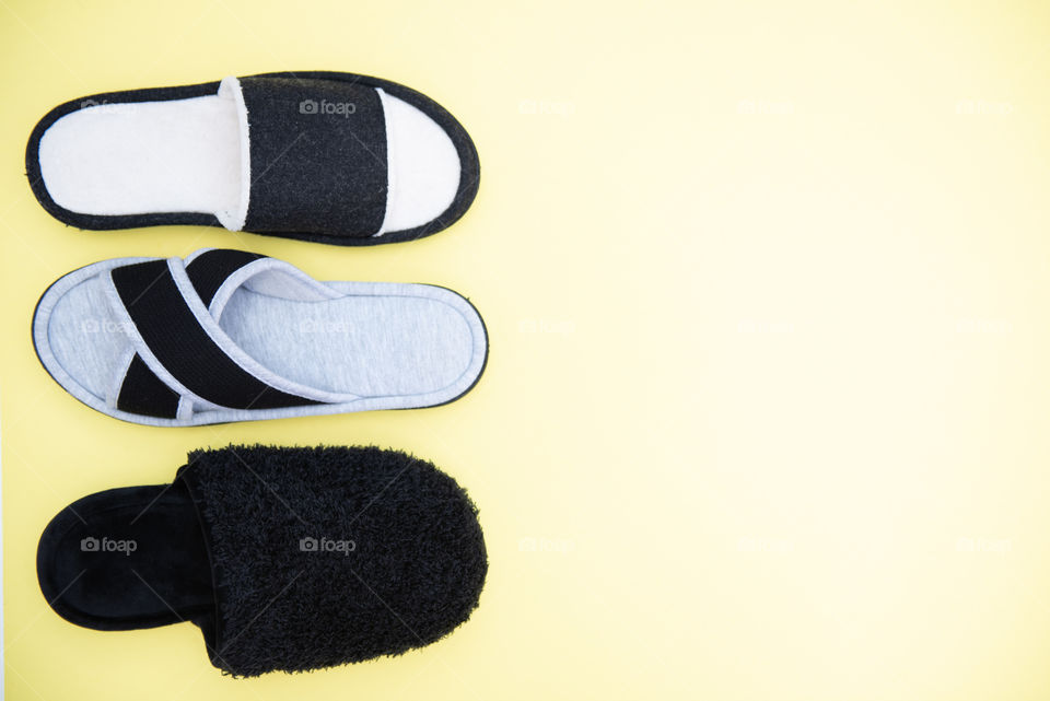 Flat lay of black slippers against a yellow background