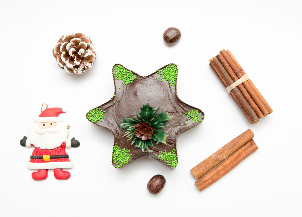 Composition Of Christmas Star Chocolate Muffin Cupcake, Santa Claus, Pine Cone, Nuts And Cinnamon Isolated On White Background
