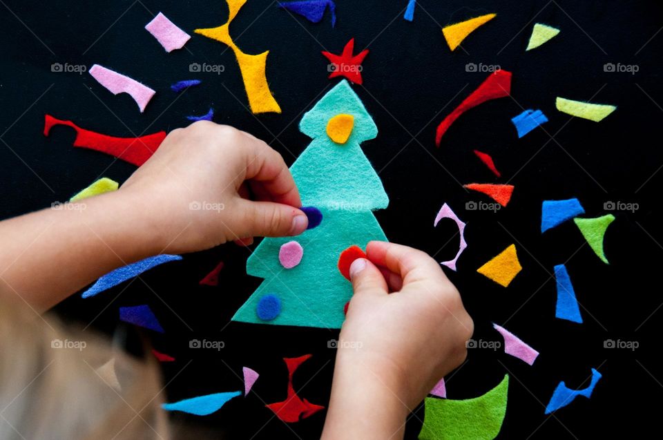 Children's hands decorate a felt homemade Christmas tree. Christmas sweets. Christmas decorations. Flat lay. Top view. Craft