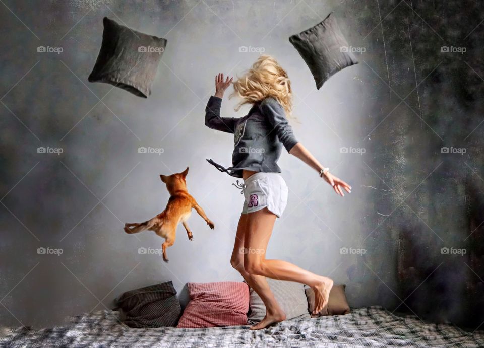 young woman jumping on the bed with her dog