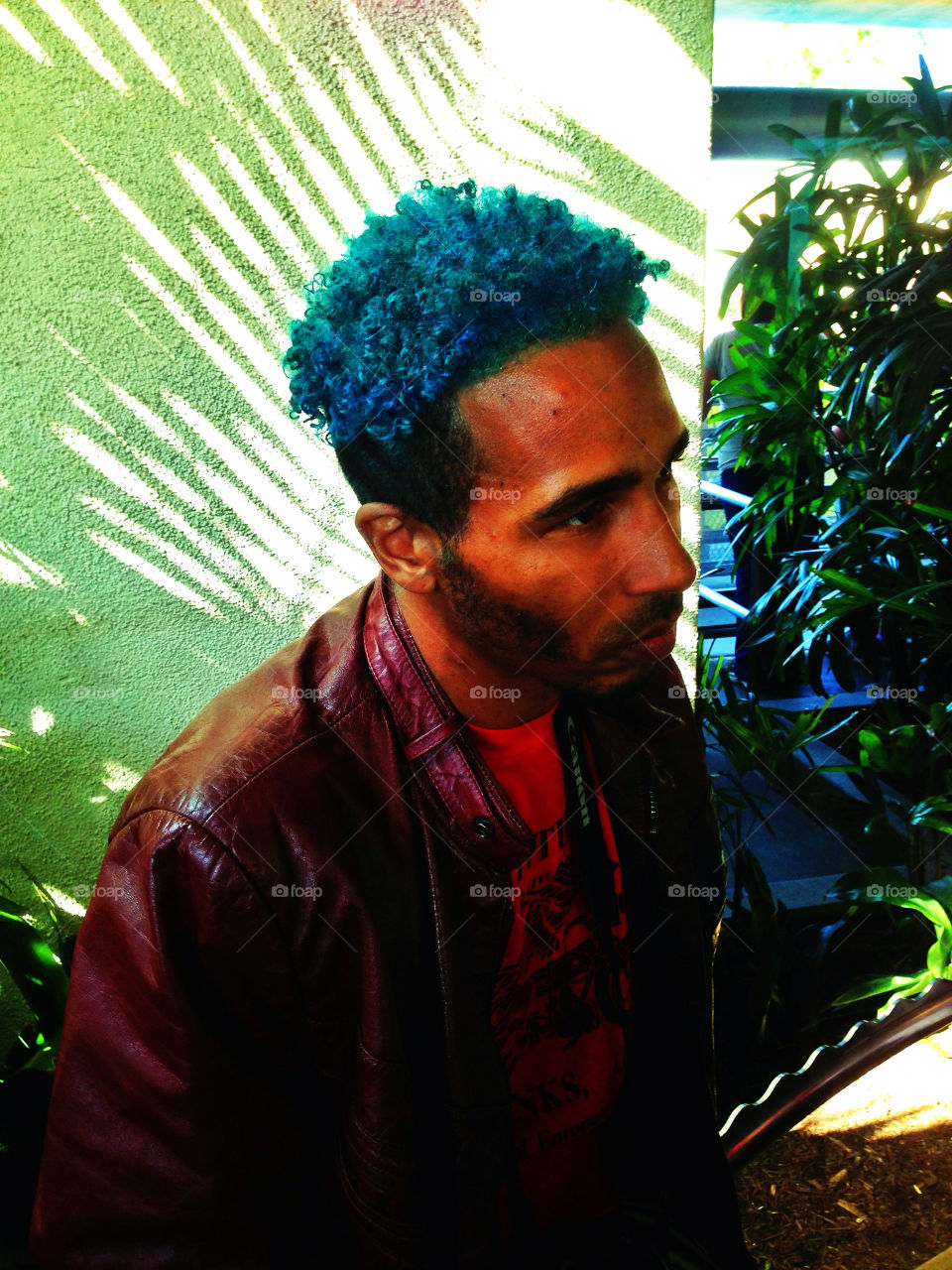 Hip African American guy with dyed blue hair in a leather jacket
