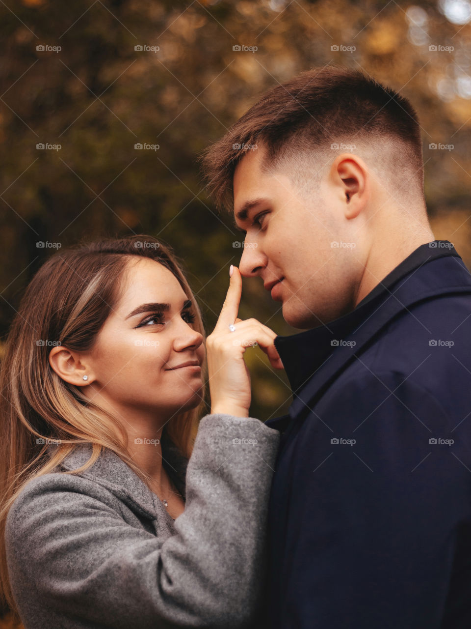 Beautiful couple - smiling girl and her boyfriend, and girl is touching the nose of a boy, autumn love story photoshoot 