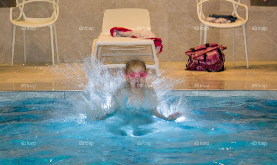 Young girl jumping in the pool.