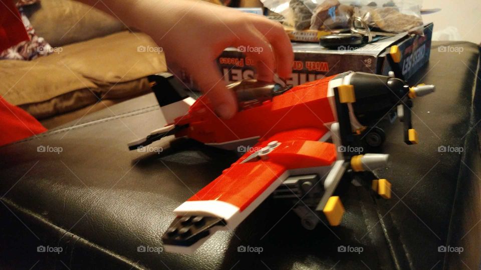 child playing with red Lego toy plane