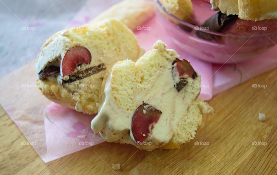 Homemade gourmet dessert Ice cream treats closeup of vanilla ice cream sandwich sliced with cherry, dark chocolate and lady fingers on wood background with pink