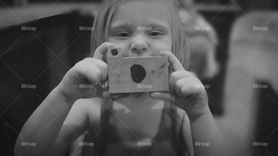 Aspiring . Girl made a camera out if scrap wood. She shows her creation to her photographer mother. 