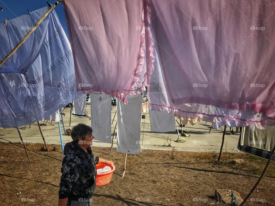 Old women taking back some clothes after washing them.
