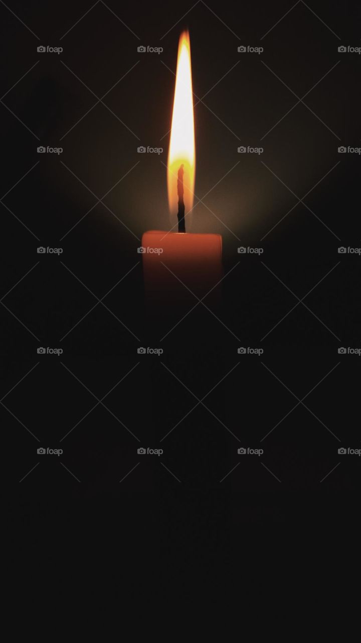 A solitary candle burns in the darkness, spreading a warm and gentle light. The steady flame contrasts with the dark background, symbolizing strength, focus, and hope in silent moments.