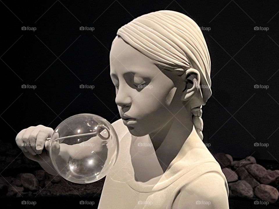 Close up of white sculpture girl blowing soap bubble 