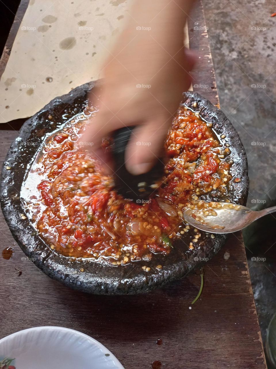 The main chili sauce is crushed so that the chili juice is released and other ingredients such as salt and shrimp paste are added