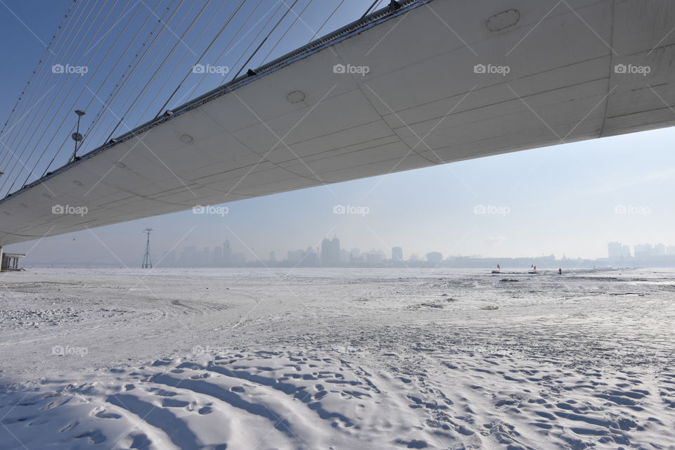Asia china  Harbin ice Festival snow Festival Harbin river frozen  view to the city of Harbin under a Bridge