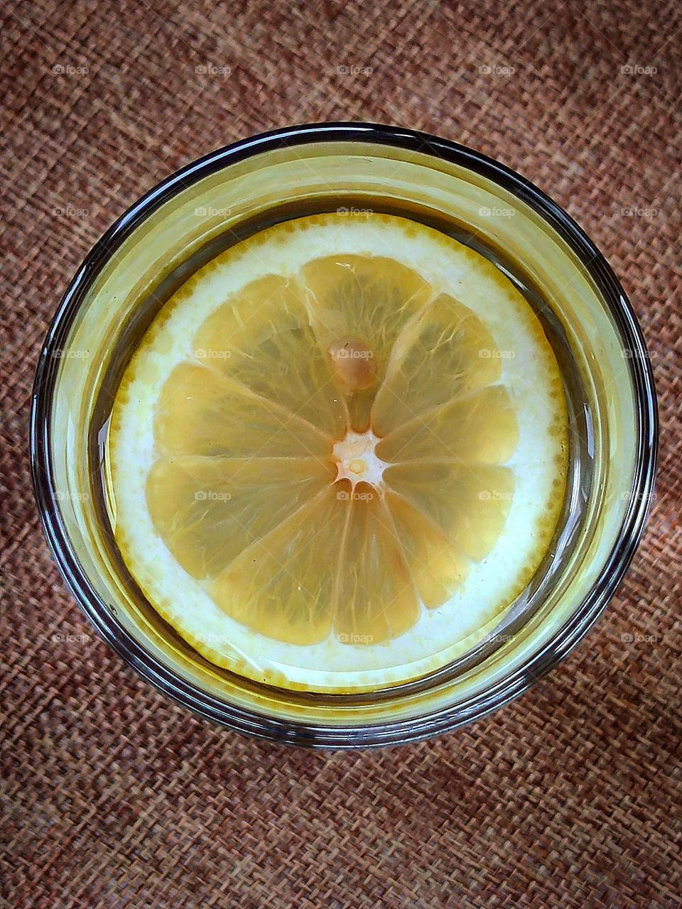 A slice of lemon in a glass of water.  View from above