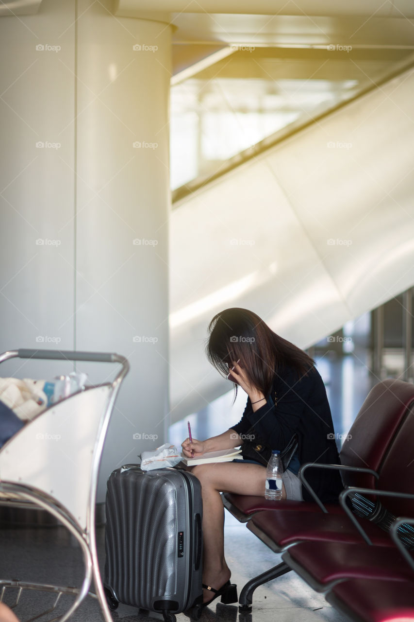 Business woman using mobile phone and waiting aircraft in the airport 