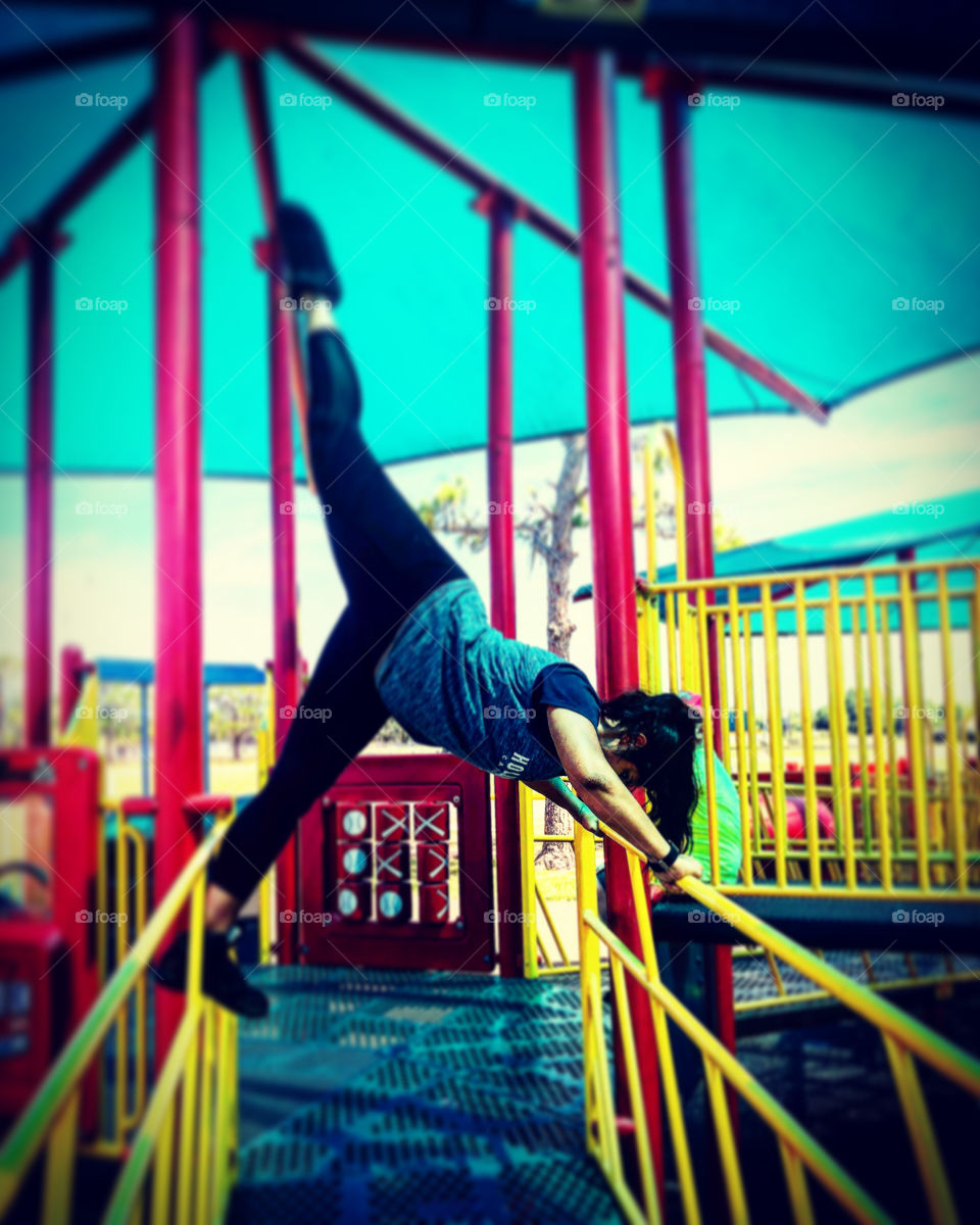 Girl doing standing split on playground equipment. Never a bad time to stretch. 