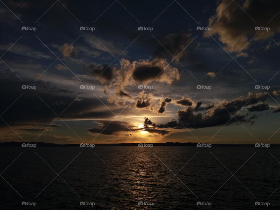 an amazing landscape of clouds, sun and sea in the late evening