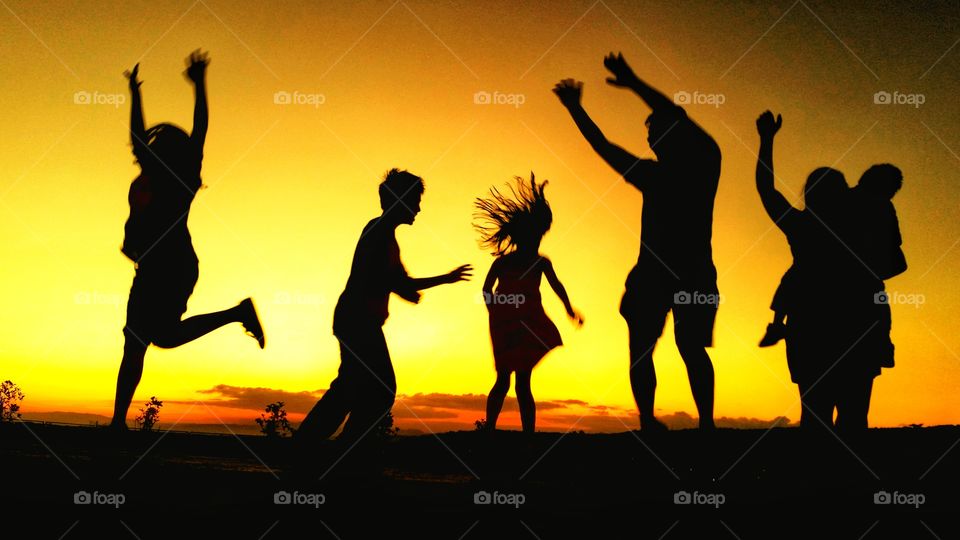 A silhouette of people in motion with the sunlight in the background.