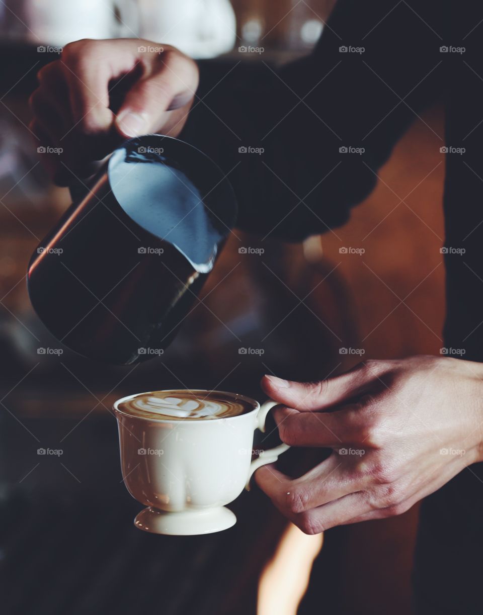 Close up to the hand of barista make a latte 