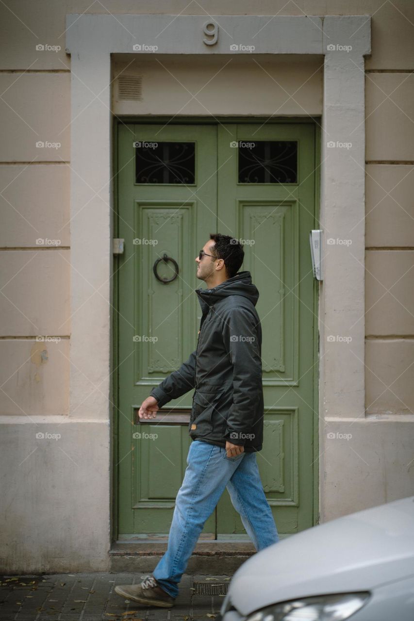 A guy walking in front of a vintage door