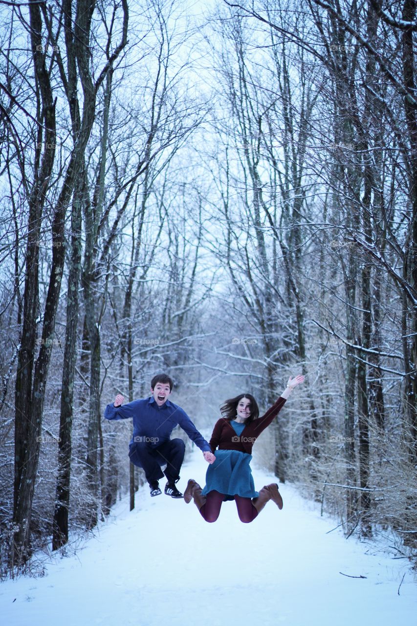 Happy young couple jumping in snowy weather
