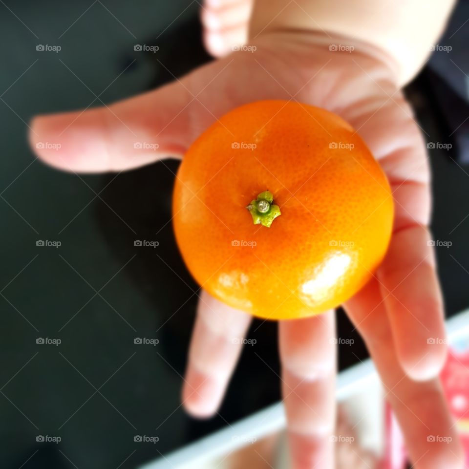 small orange in tiny hand