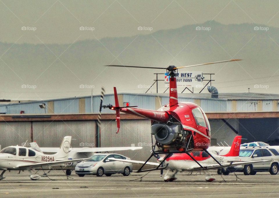 Helicopter Preparing For Liftoff. Robinson R-22 Helicopter Hovering Over An Airfield
