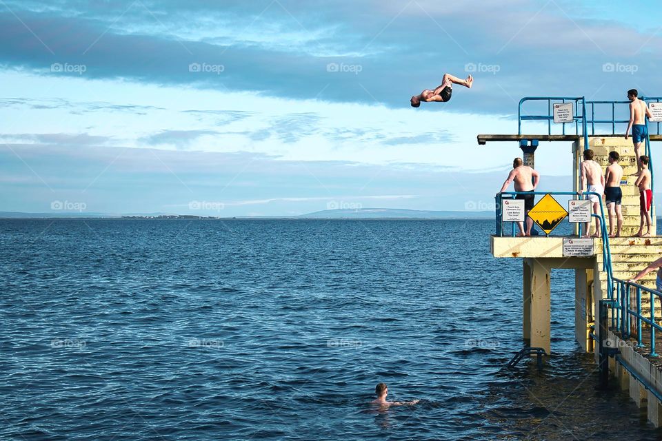 Man jumping back flip from Blackrock diving tower at Salthill beach in Galway, Ireland