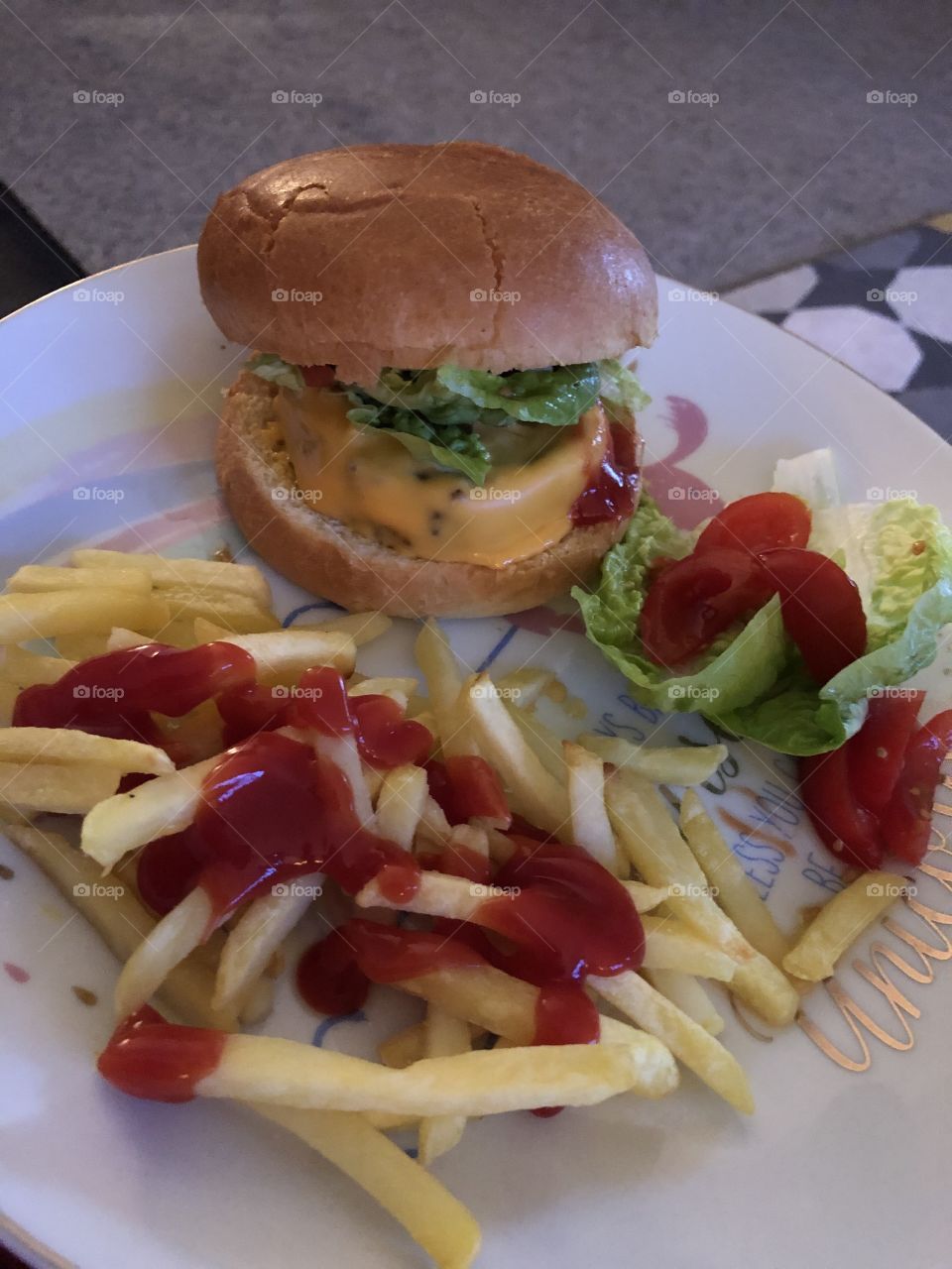 Homemade cheese burger with ketchup on fries and side salad 