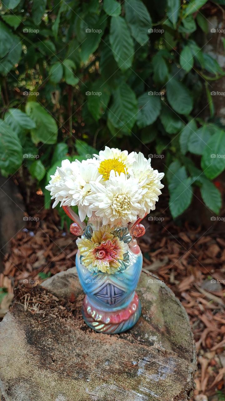 Beautiful white flowers in a colourful flowerpot with a flower sculpture, Flowers in a vase, colourful vase, white flowers in a vase