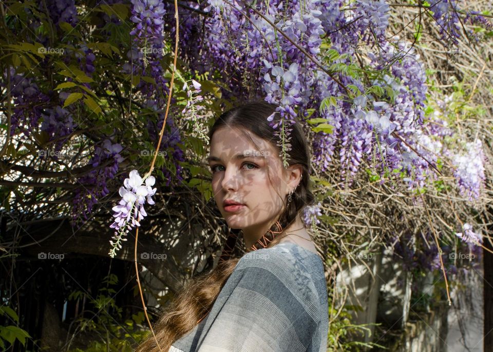 Portrait of Young Girl on Background of Purple Flowers