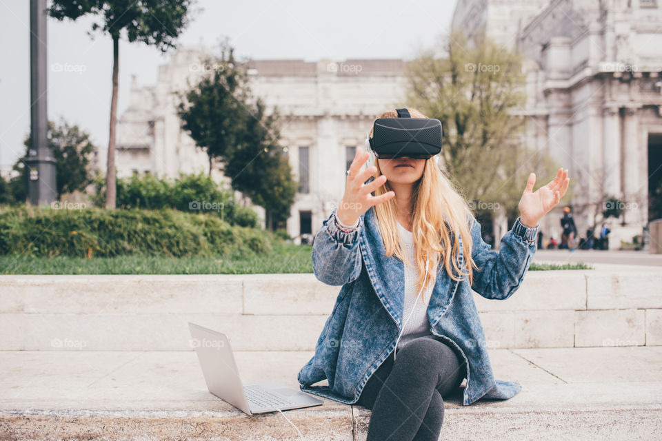 woman using notebook and virtual reality viewer in the street - technology, gaming, virtual reality concepts
