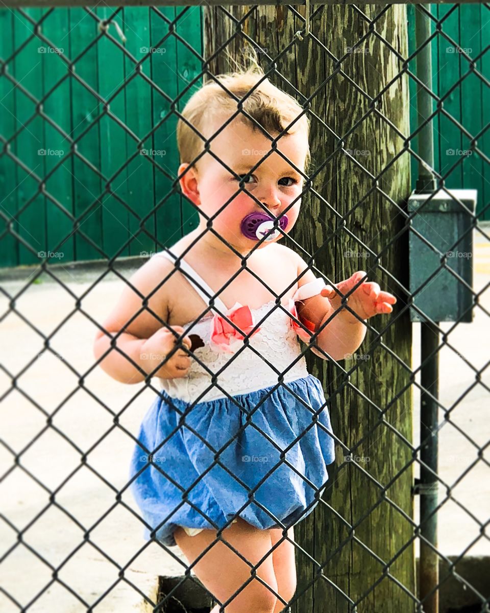 Little girl watching through a fence