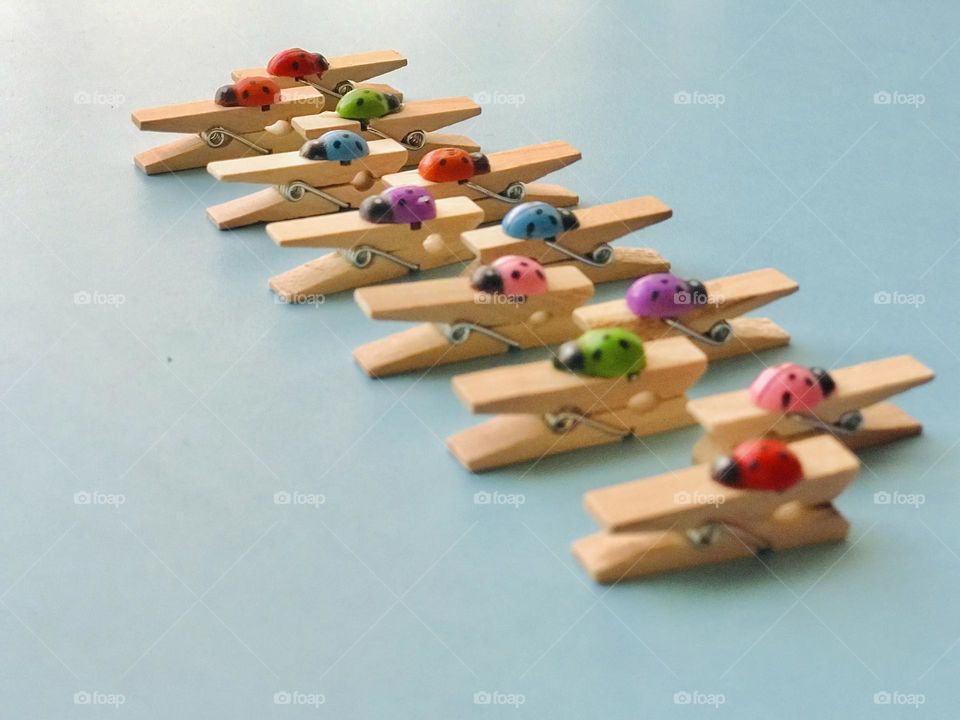 Colourful ladybug wooden clips arranged in zigzag row.